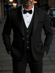 A man wearing a black three-piece suit with a shawl collar jacket, vest, and bow tie.