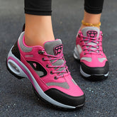A pair of pink and black lace-up sneakers with air-cushioned soles worn on feet.