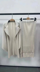 A cream-colored pleated two-piece set featuring a batwing sleeve jacket and a tasseled skirt.