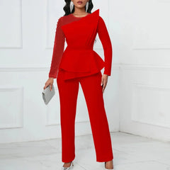 A woman wears a red long-sleeved jumpsuit with a beaded mesh sleeve and a layered peplum waist.