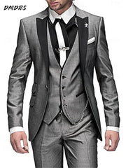 A man wears a three-piece grey suit with a black lapel, black shirt, and white tie.