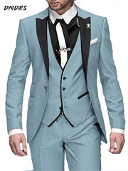 A man wears a light blue three-piece suit with a black vest, black lapels, and a white tie.