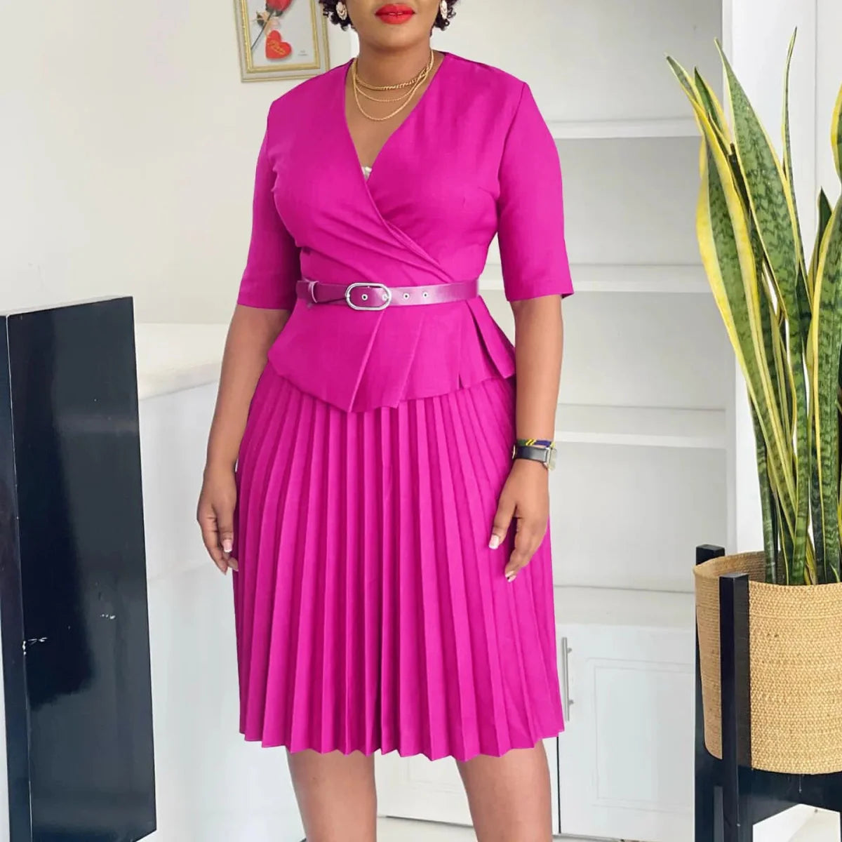 A magenta V-neck midi dress with half sleeves, a pleated skirt, and a matching waist belt.