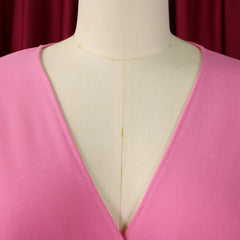 A close-up view of the V-neckline on a solid pink professional dress worn by a mannequin.