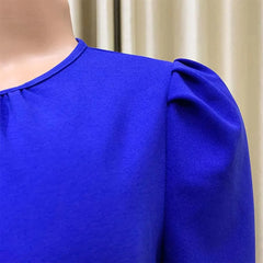 A close-up of a royal blue midi dress featuring a round neckline and pleated puff sleeves.