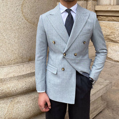 A man wears a light blue pinstriped double-breasted suit jacket with a white shirt and dark tie.