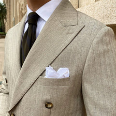 A tan double-breasted suit jacket with vertical stripes, a white pocket square, and a dark tie.