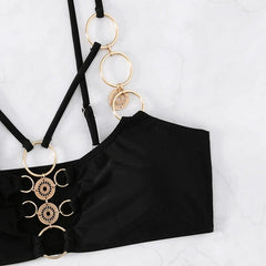 A black bikini top featuring decorative gold-toned metal rings and adjustable straps.