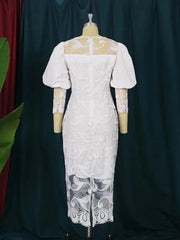 A white midi-length lace sheath dress featuring puff sleeves and intricate floral embroidery.