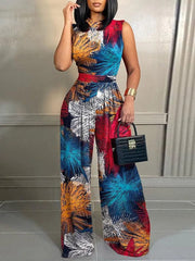 A woman wears a sleeveless, wide-leg jumpsuit featuring a colorful, abstract floral print.