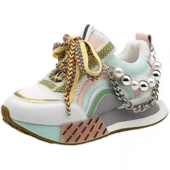 A white platform sneaker featuring colorful laces, pastel accents, and a decorative pearl chain.