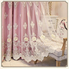 Pink curtains featuring intricate white floral embroidery and a scalloped lace hem.