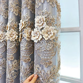 A grey curtain featuring intricate gold floral embroidery and three-dimensional fabric flowers.