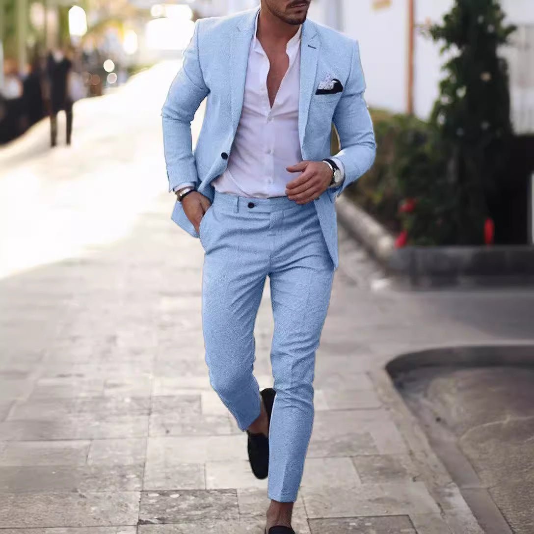 A man wears a light blue slim-fit suit with a white button-down shirt and black loafers.