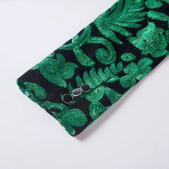 A close-up of a green velvet blazer sleeve featuring intricate sequin embroidery and three buttons.