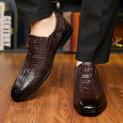 A pair of dark brown, slip-on men's dress shoes with a glossy, embossed crocodile-skin texture.