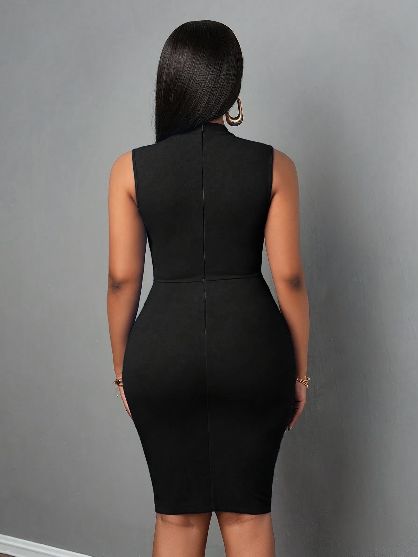 A woman from behind wears a black sleeveless midi bodycon dress with a high neckline.