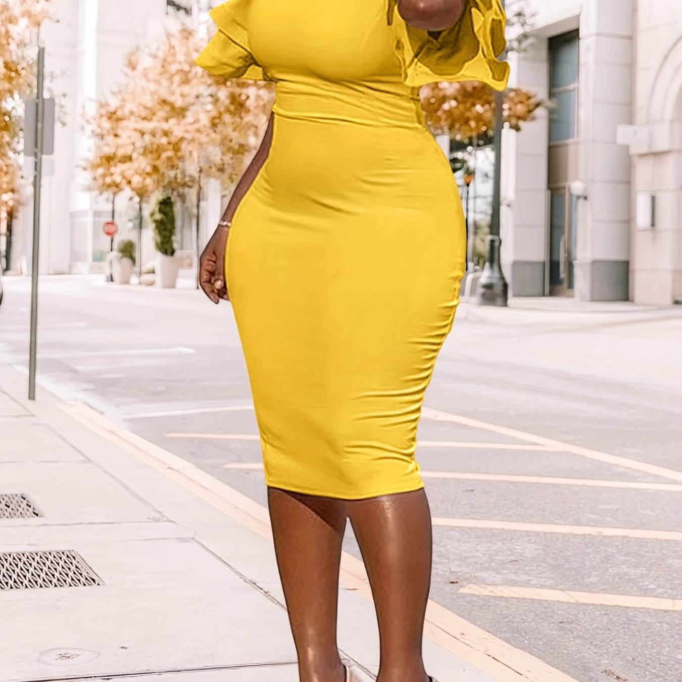 A woman wears a yellow midi-length bodycon pencil dress with short ruffle sleeves.