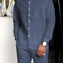 A man wears a blue minimalist business suit with a stand collar shirt and straight-cut pants.