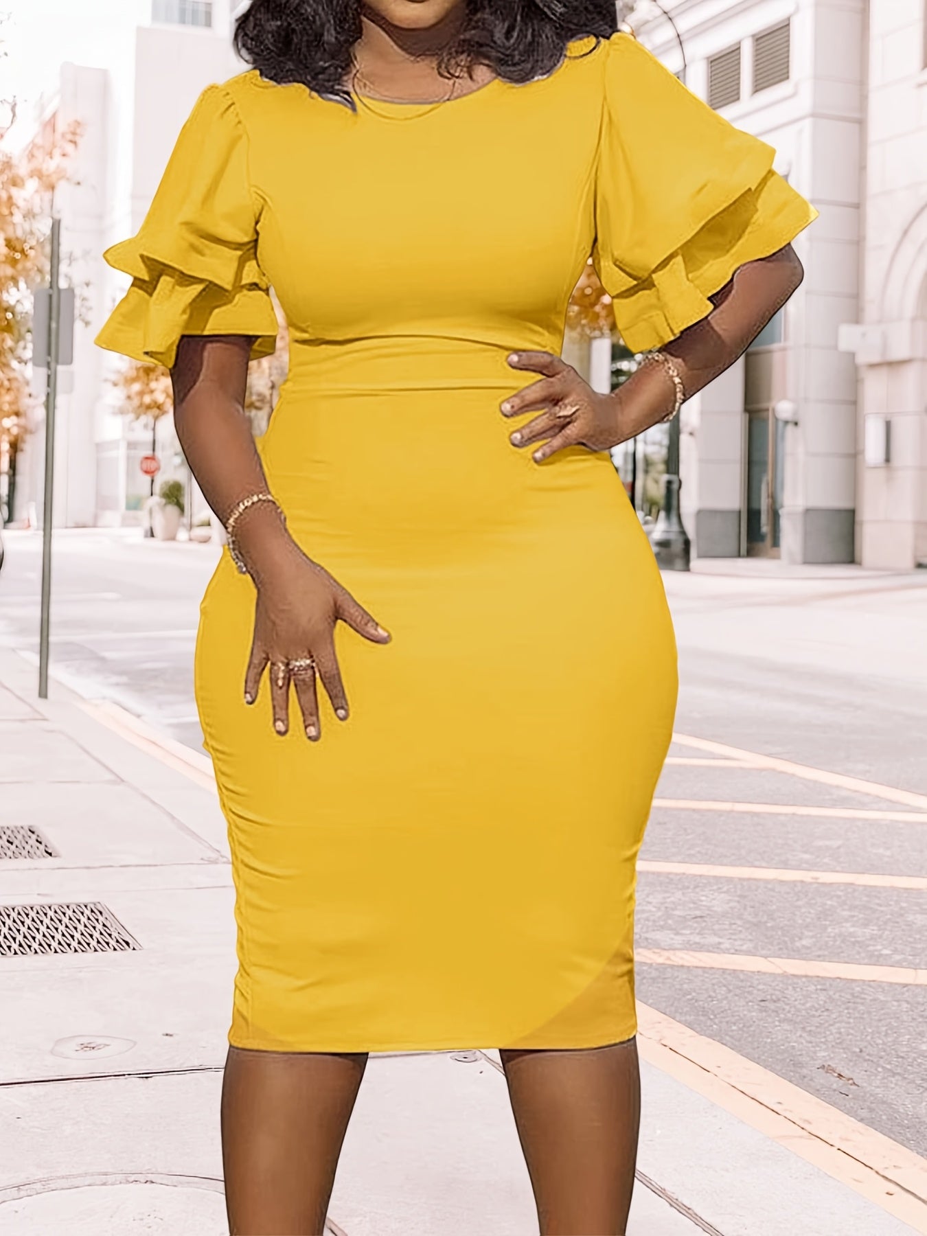 A woman wears a solid yellow midi-length pencil dress featuring a round neckline and ruffled short sleeves.