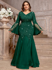 A plus-size emerald green V-neck gown featuring sequined lace, long bell sleeves, and a tulle hem.