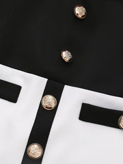 A close-up of a black and white color-blocked jacket featuring gold embossed buttons.