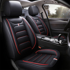 Black faux leather car seat covers with red piping and small tricolor accents.