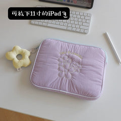 A light purple quilted tablet sleeve featuring embroidered flowers and a matching flower charm.