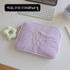 A light purple quilted tablet sleeve featuring embroidered flowers and a matching flower-shaped keychain.