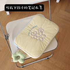 A yellow quilted laptop sleeve with purple flower embroidery and a matching flower charm.