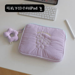 A light purple quilted tablet sleeve featuring embroidered flowers and a matching flower charm.