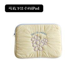 A light yellow quilted tablet sleeve featuring embroidered purple flowers and the text two flowers.