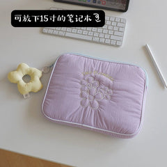 A light purple padded laptop sleeve featuring embroidered flowers and a matching flower charm.