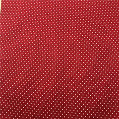 A close-up view of red fabric featuring a repeating pattern of small white polka dots.