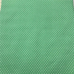 A green fabric featuring a repeating pattern of small white polka dots.