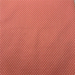 A close-up view of fabric featuring a repeating pattern of small white dots on a coral background.