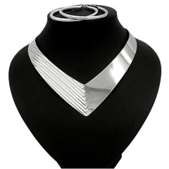 A silver-toned V-shaped collar necklace with a textured side and a smooth side on a black display.