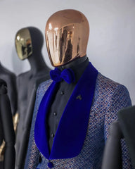 A blue patterned tuxedo jacket with a velvet shawl lapel and matching bow tie on a mannequin.