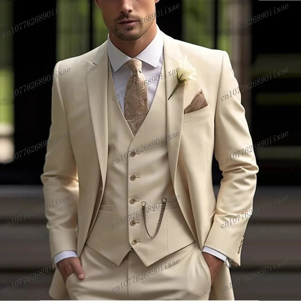 A man wears a formal three-piece beige suit with a patterned tie and pocket square.