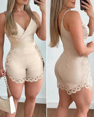 A beige sleeveless romper with a V-neck, spaghetti straps, and decorative lace trim on the sides.