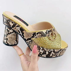 A gold and snake-print platform mule with a round heel and rhinestone-studded front strap.
