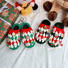Two pairs of handmade crochet Christmas slippers decorated with festive charms on a white surface.