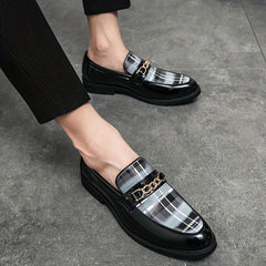 Men's black patent leather loafers featuring a grey plaid pattern and a gold-tone chain detail.