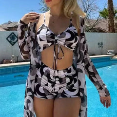 A woman wears a black and white patterned tankini set with a matching long-sleeved cover-up.