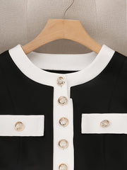 A black and white color block jacket featuring a crew neck and gold button details.