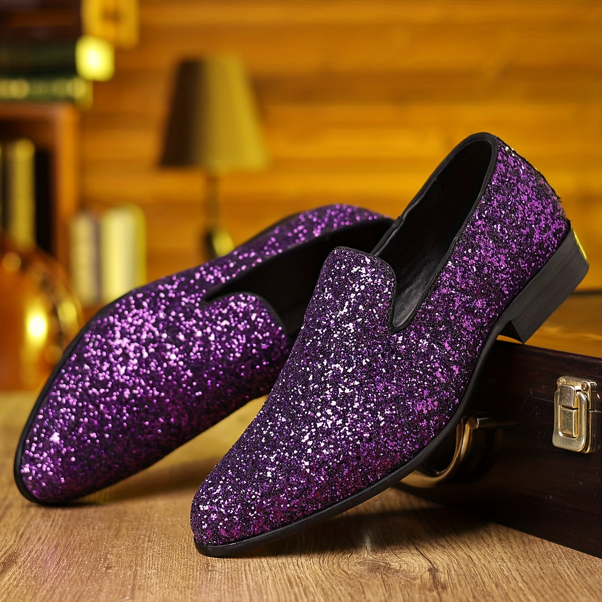A pair of purple glittery slip-on dress shoes with a pointed toe resting on a wooden surface.