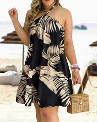 A woman wears a black halter neck mini dress featuring a beige tropical leaf print.