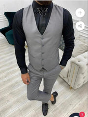 A man wearing a slim-fit grey three-piece suit with a black shirt and tie.