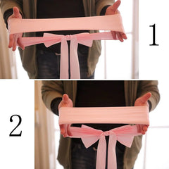 A person holds a light pink elastic fabric chair sash with a pre-tied bow.