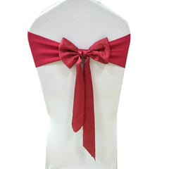 A red satin chair sash tied in a bow around a white chair cover.